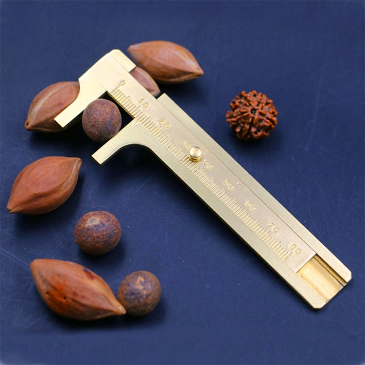 Brass sliding vernier caliper with engraved scale, displayed with mixed beads