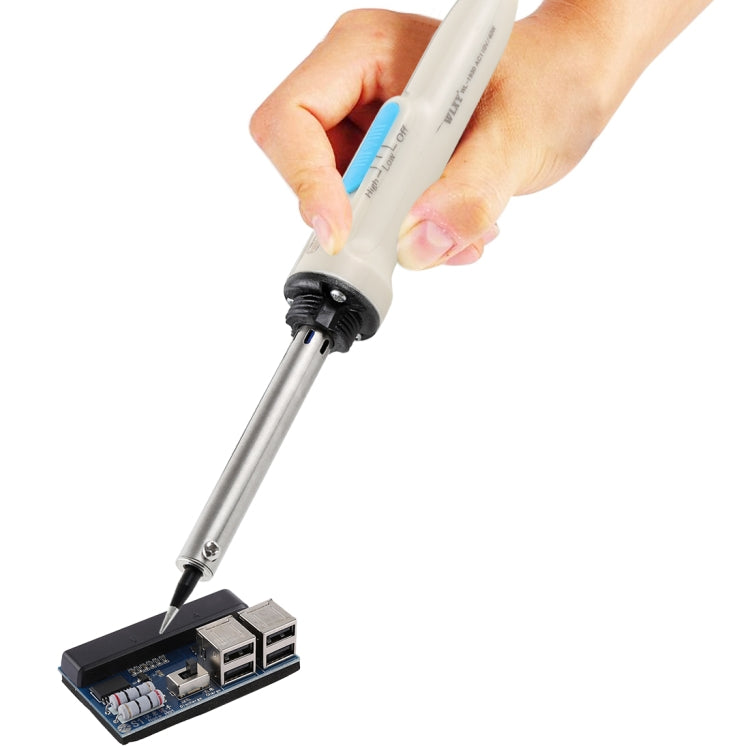Hand holding soldering iron with metal tip near circuit board
