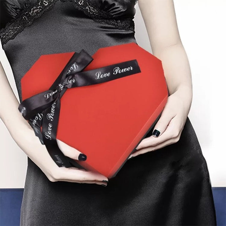 Person holding red heart-shaped gift box with black ribbon bow and “Love Forever” text.