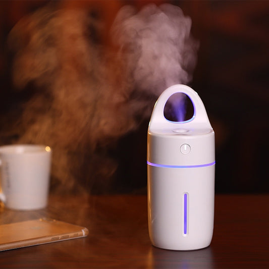 Mini portable humidifier on table, white with purple-toned LED mist glow