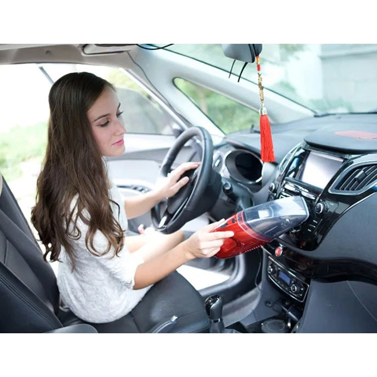 Woman using a red handheld vacuum cleaner inside a car to clean the dashboard area