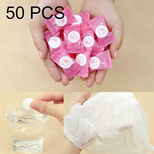 Set of 50 pink disposable travel cotton towels in candy-style wrappers, in hands