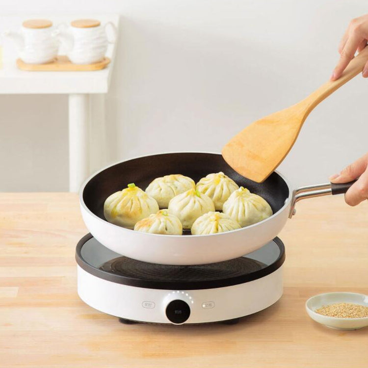 Electric nonstick frying pan cooking dumplings, black interior on white base