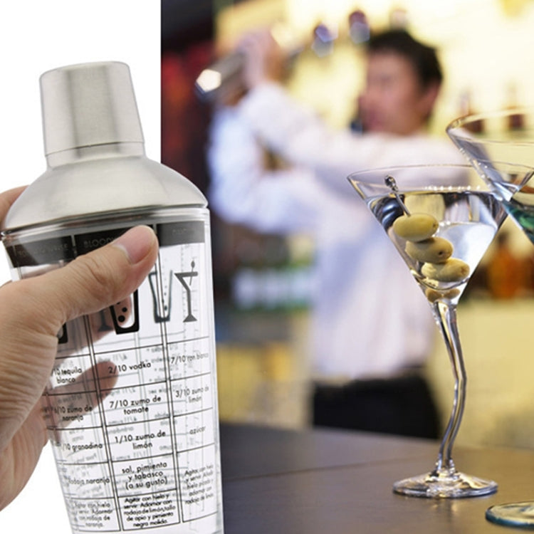 Hand holding clear cocktail shaker with stainless cap and built-in measurement scale