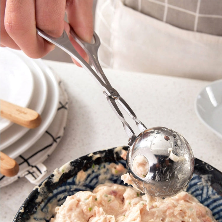 Stainless steel meatball maker scoop pressing into a bowl of mixture