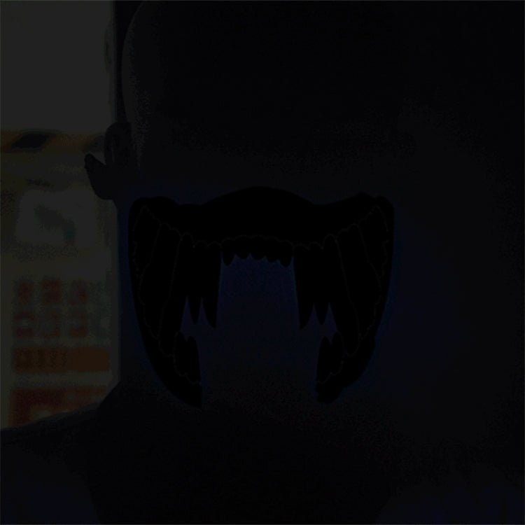 Dark LED face mask with blue glow teeth pattern, low-light view