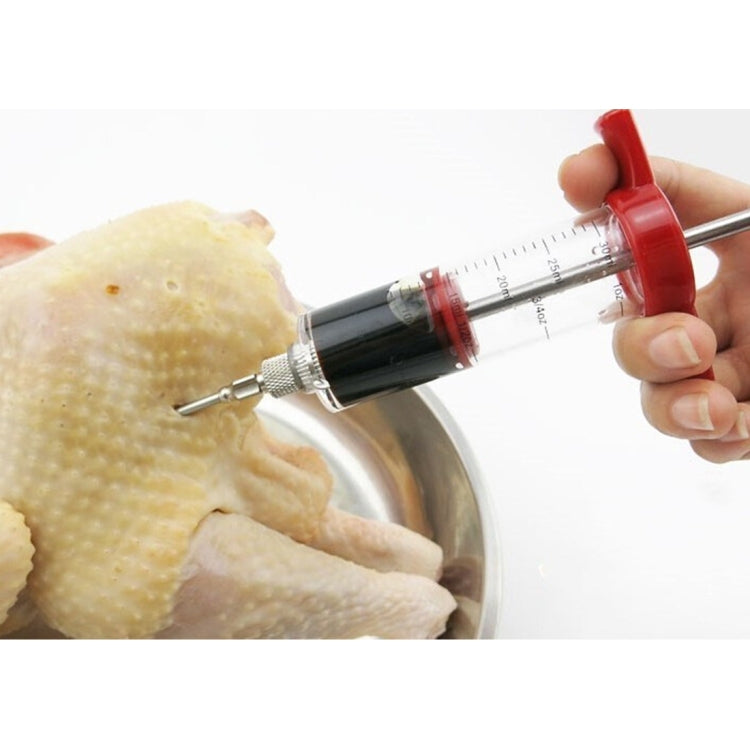 Plastic marinade injector syringe with red handle held in hand, metal needle