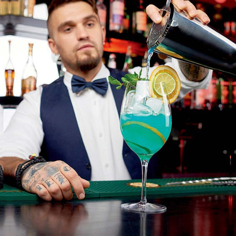 Stainless steel shaker pouring into a cocktail glass with citrus garnish