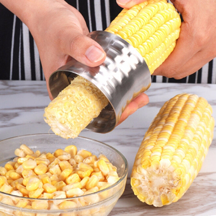 Stainless steel corn stripper shaving kernels from a yellow corn cob