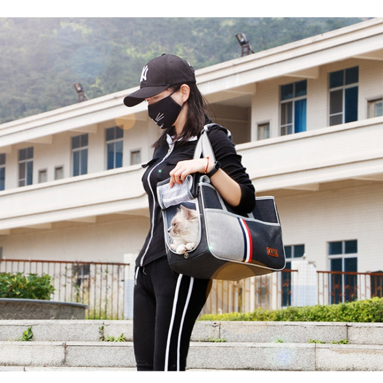 Grey pet carrier bag with mesh front panel and striped side, carried by shoulder strap