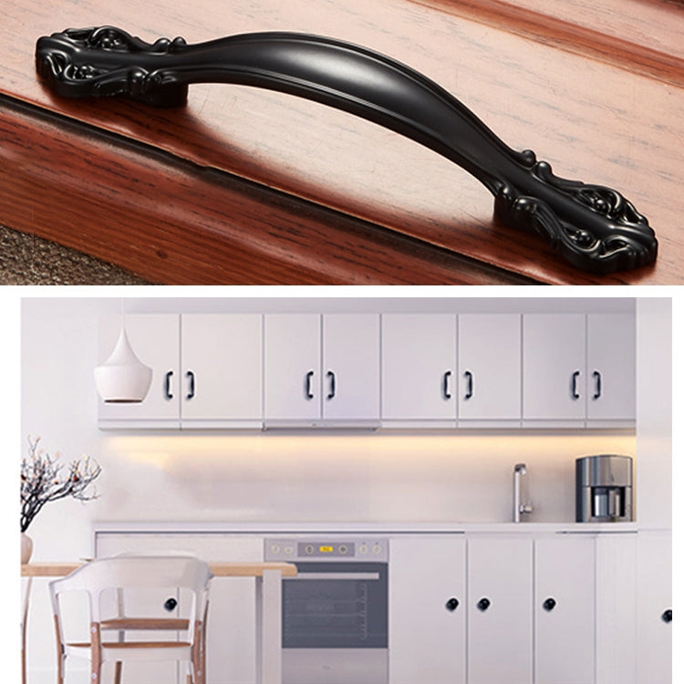 Black curved cabinet handle on a wooden drawer