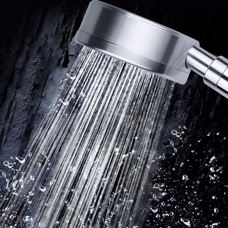 Silver handheld shower head spraying a fine mist from the round spray face