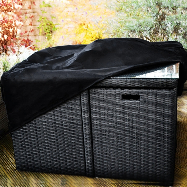 Black protective cover draped over wicker outdoor table and chair set