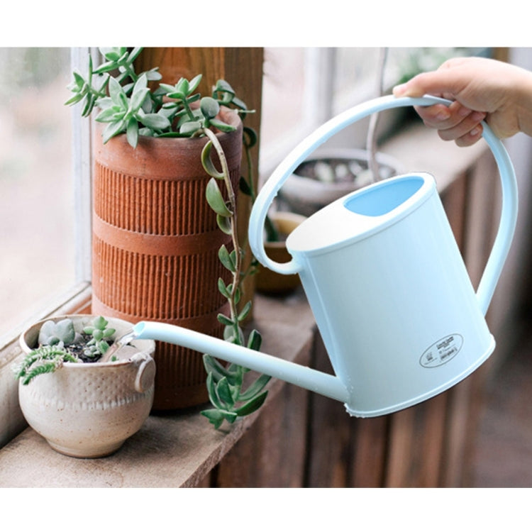 Light blue plastic watering can with long spout and curved handle by potted plants