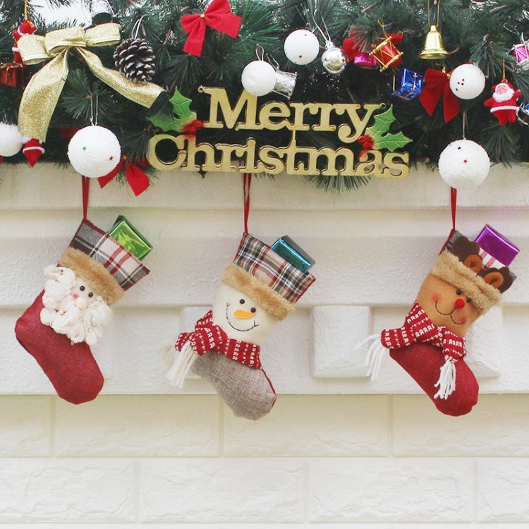 Three hanging Christmas stockings with plaid cuffs, character faces, and gift boxes