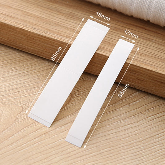 Two white adhesive strips with size measurements on a wooden surface