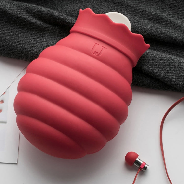 Red silicone hot/cold water bag with cap, placed on fabric with cord nearby