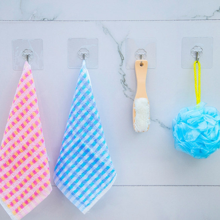 Multiple clear flower-shaped adhesive hooks with hanging towels and sponges on wall