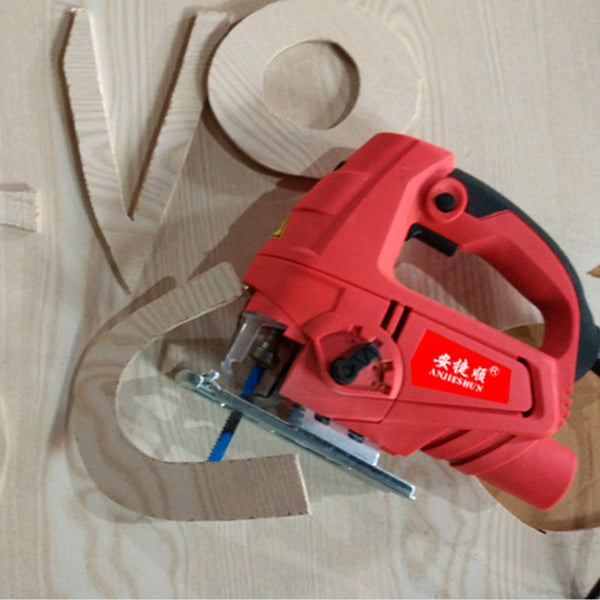 Red electric jig saw cutting a wooden board on a light surface