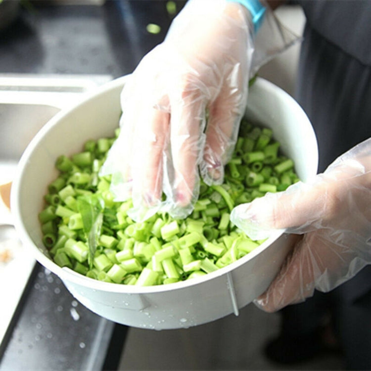 Transparent disposable PVC gloves on hands handling chopped vegetables