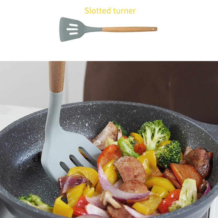 Slotted silicone cooking shovel with wooden handle stirring vegetables in pan