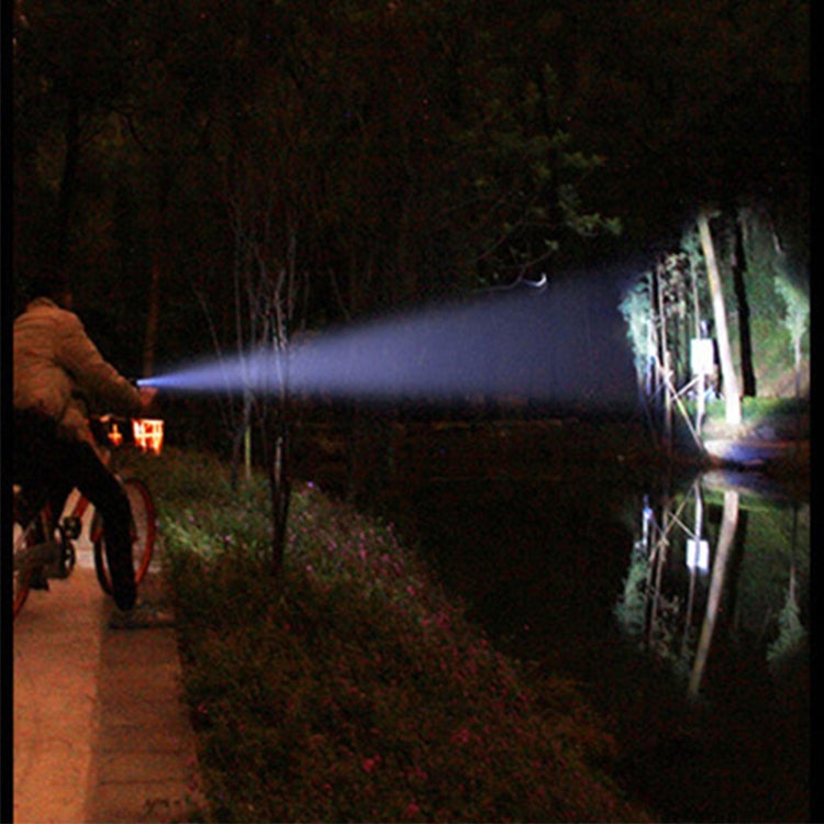 Handheld LED flashlight casting a long bright beam outdoors at night