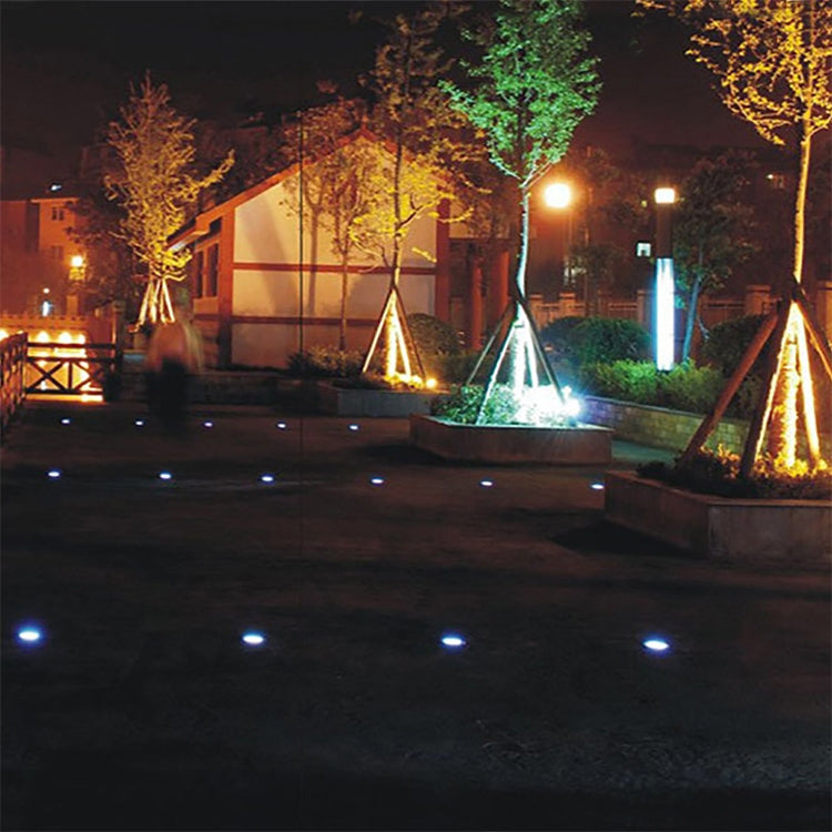 Set of solar-powered buried garden spotlights, emitting white light for landscape illumination