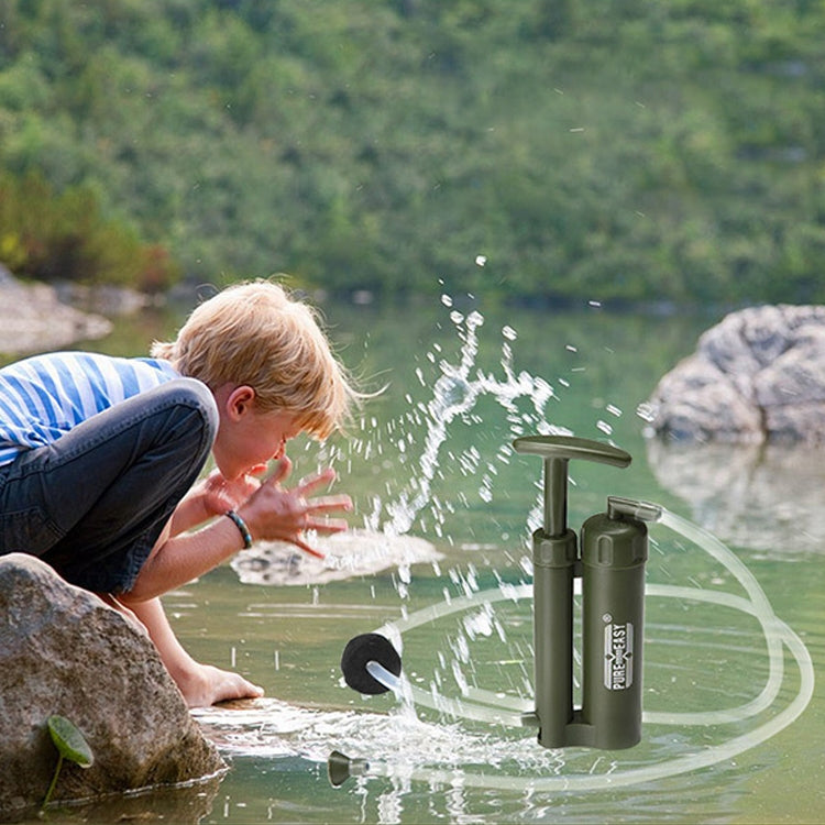 Portable water filter pump dispensing water with clear hose near outdoor rocks