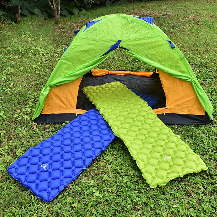 Blue and green inflatable camping air mattress cushions laid on grass beside tent.