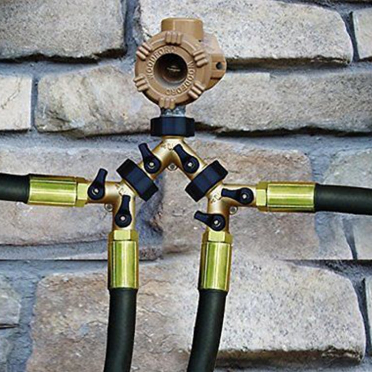 Brass water tap valve shunt connector on outdoor wall with hoses and control knob