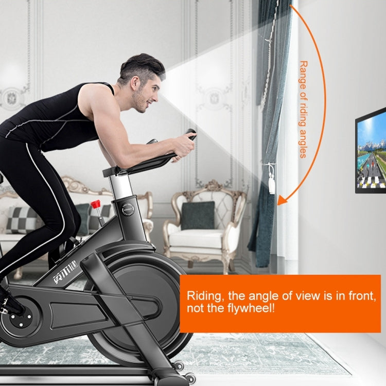 Indoor spinning bicycle in home setting, rider leaning forward
