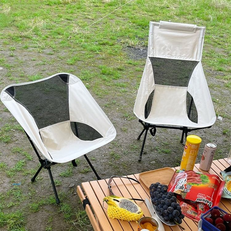 White folding camping chair with mesh backrest, black legs, near outdoor picnic items.