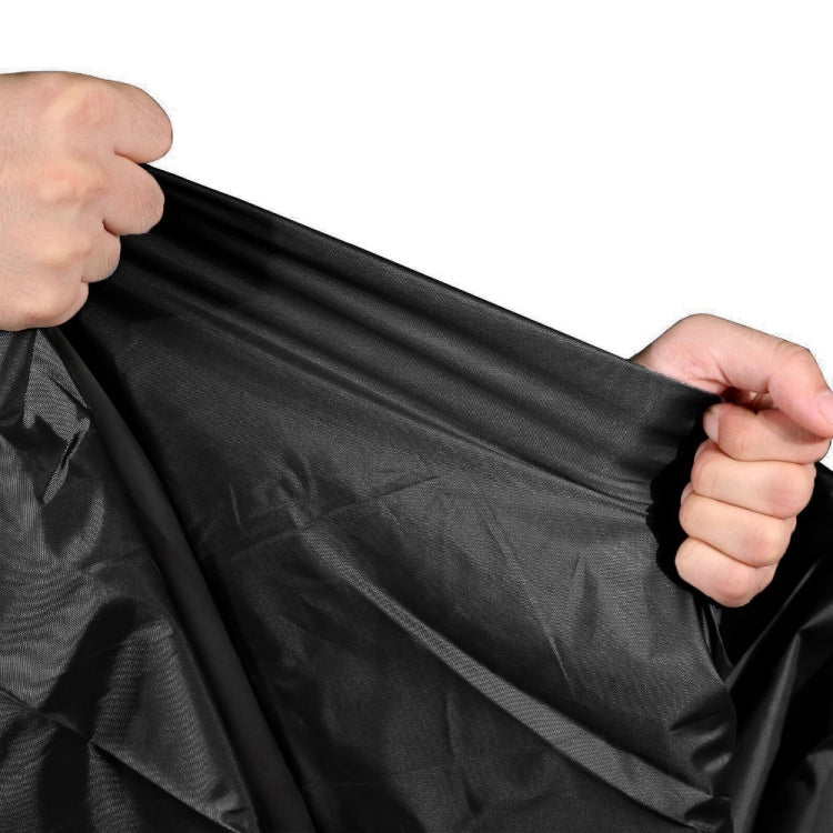 Hands holding black BBQ grill cover with adjustable drawstring hem and straps