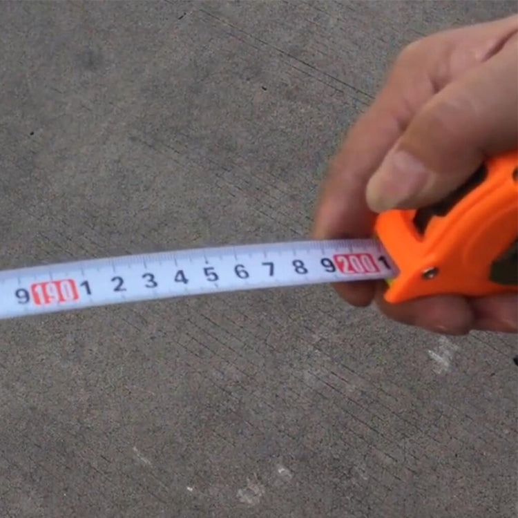 Orange tape measure extended by hand against a gray surface