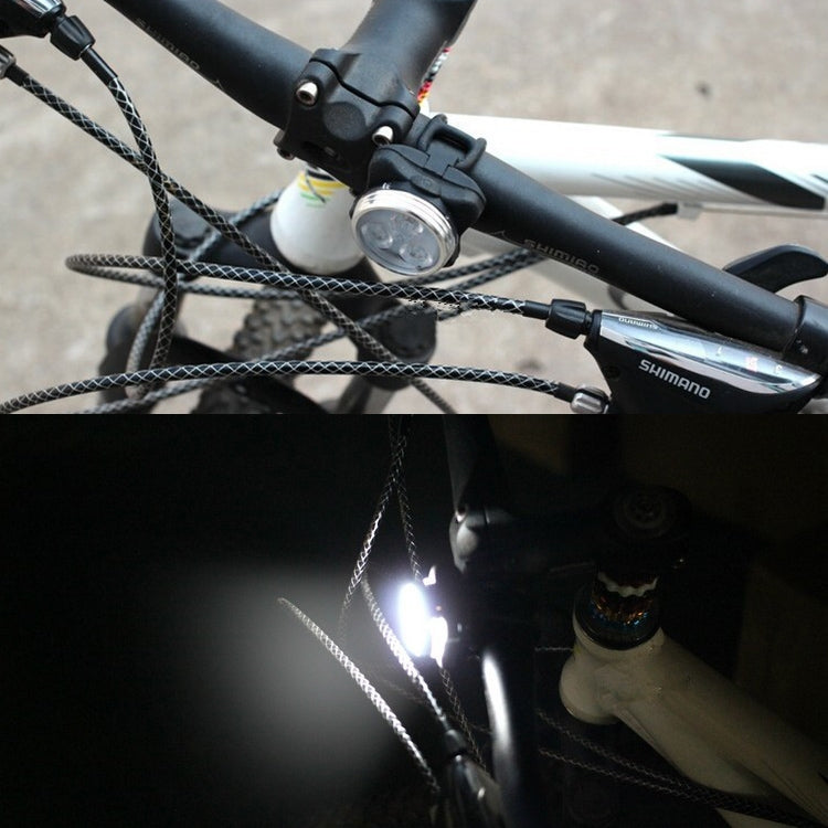 White bicycle headlight mounted on handlebars, light beam shining
