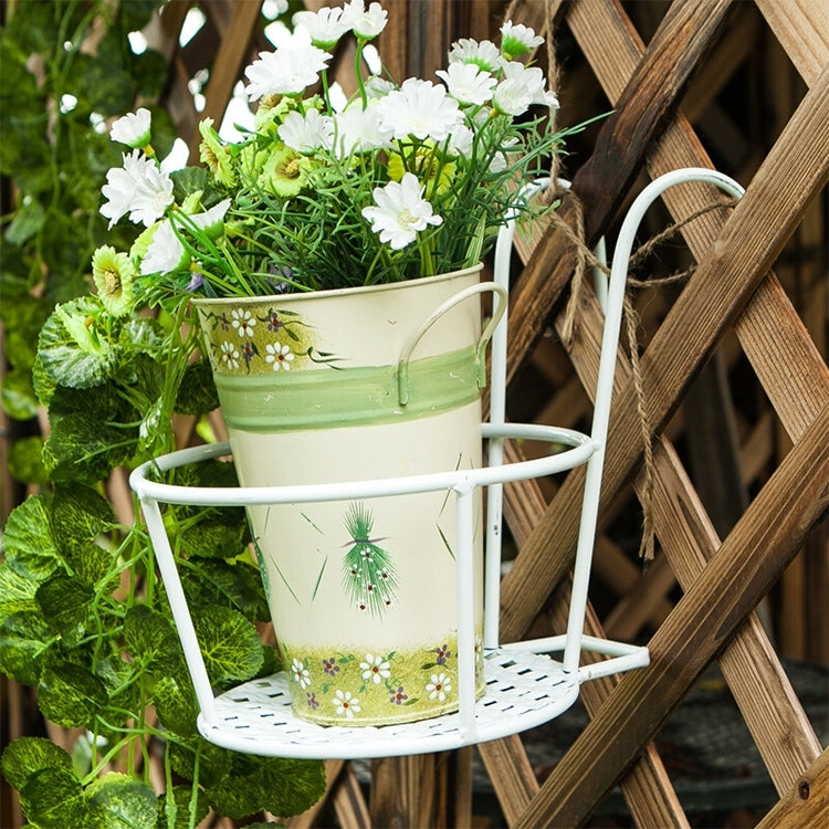 White metal hanging flowerpot rack holding a white pot with green and white flowers