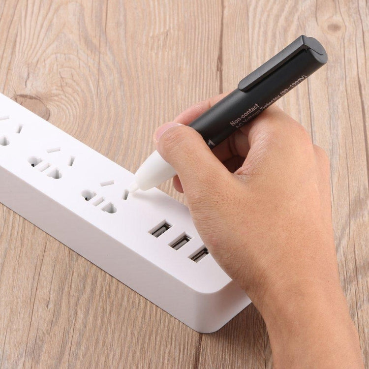 Non-contact voltage tester pen in hand, black body with white probe tip