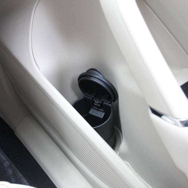 Black portable car ashtray in console cup holder, lid and mounting visible.