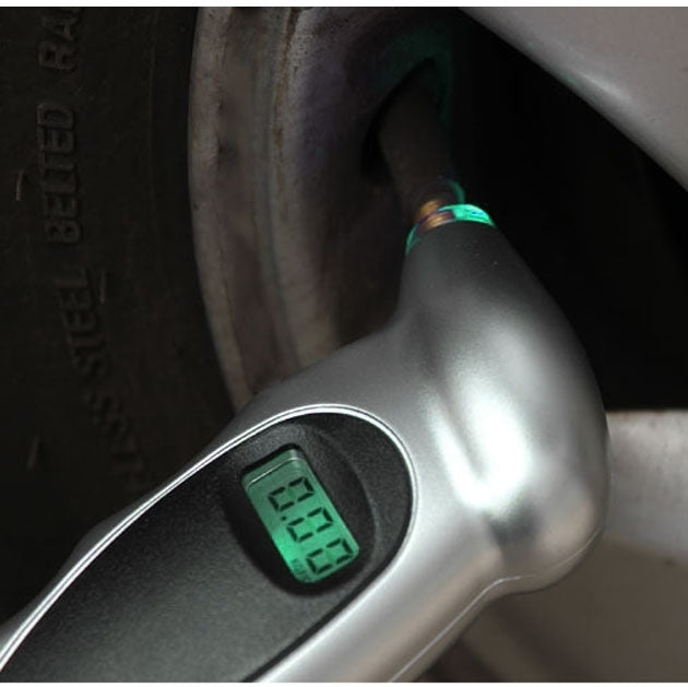 Close-up of silver digital tire gauge showing green LCD PSI display