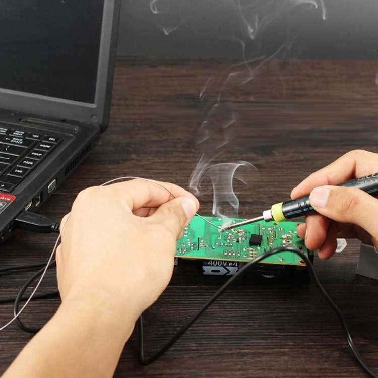 USB soldering iron pen heating a green circuit board during repairs