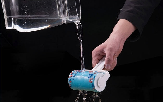 Silicone hair remover roller being rinsed with water, blue drum and white handle.