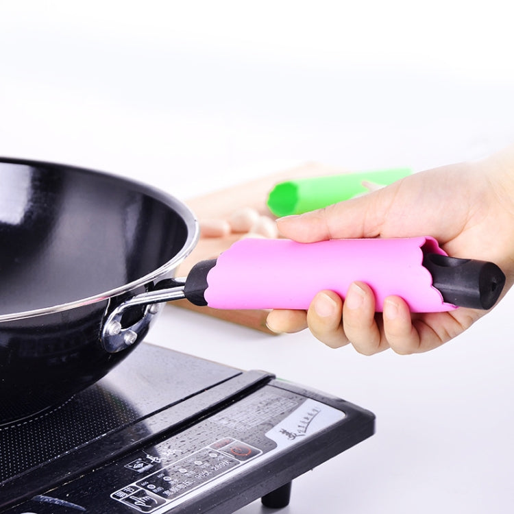 Pink silicone garlic peeler roller tube in hand beside a pot on the stovetop