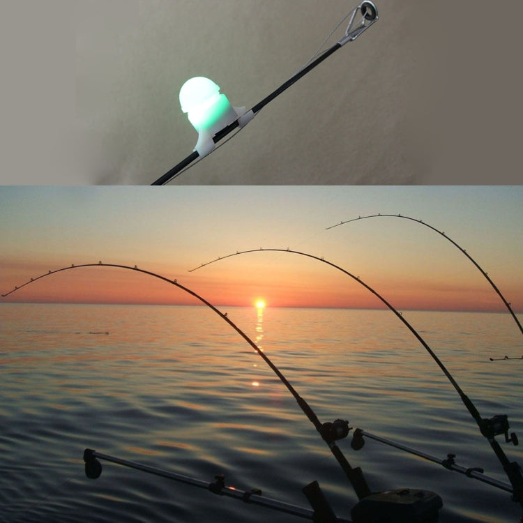 Fishing rod set at dusk with glowing green bite alarm light on the line