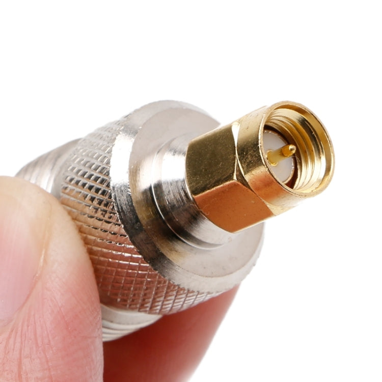RF coaxial adapter close-up, silver housing with gold male contact and threaded socket