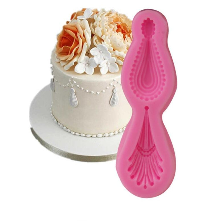 Pink silicone gemstone pendant mold next to a decorated fondant cake with small pendant accents