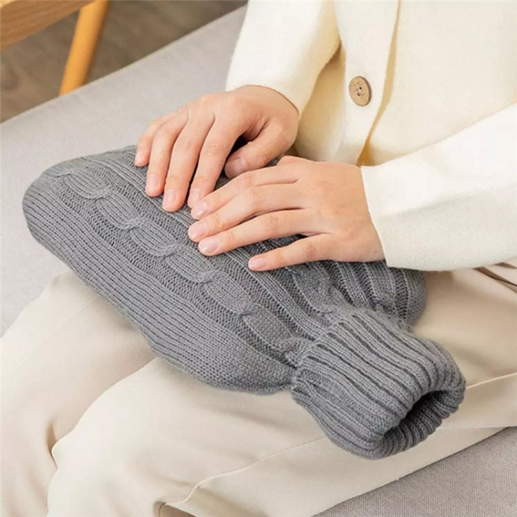 Deep gray knitted hot water bottle cover held on a sofa cushion; ribbed collar