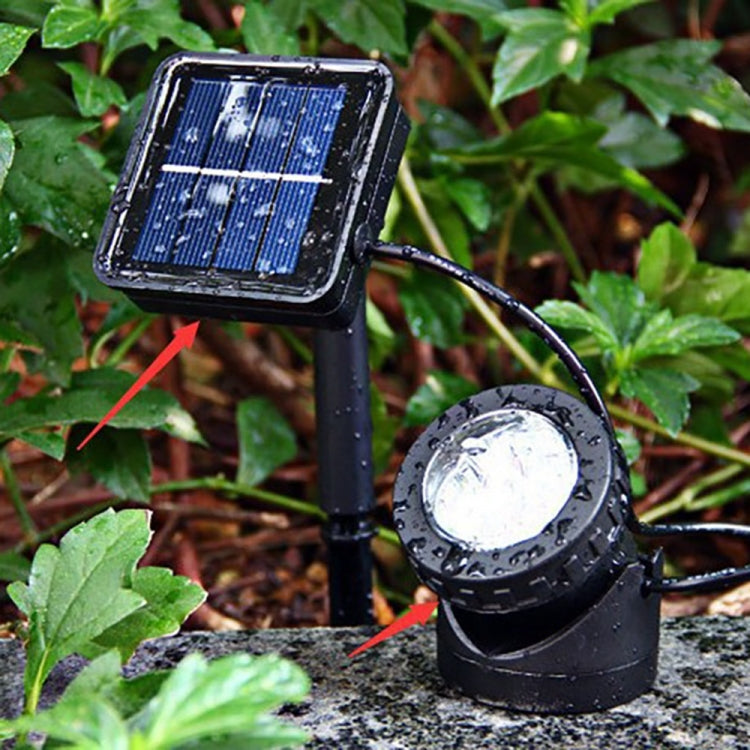 Outdoor solar spotlight and solar panel set in a garden among leaves, black finish