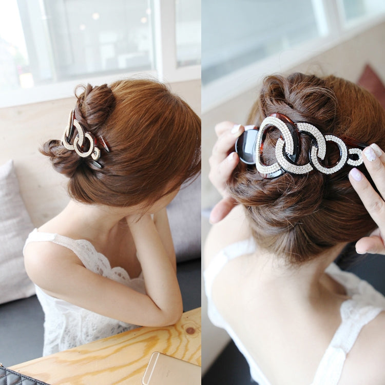 Rhinestone hair claw clip worn in a bun, large linked oval sparkle hair accessory.