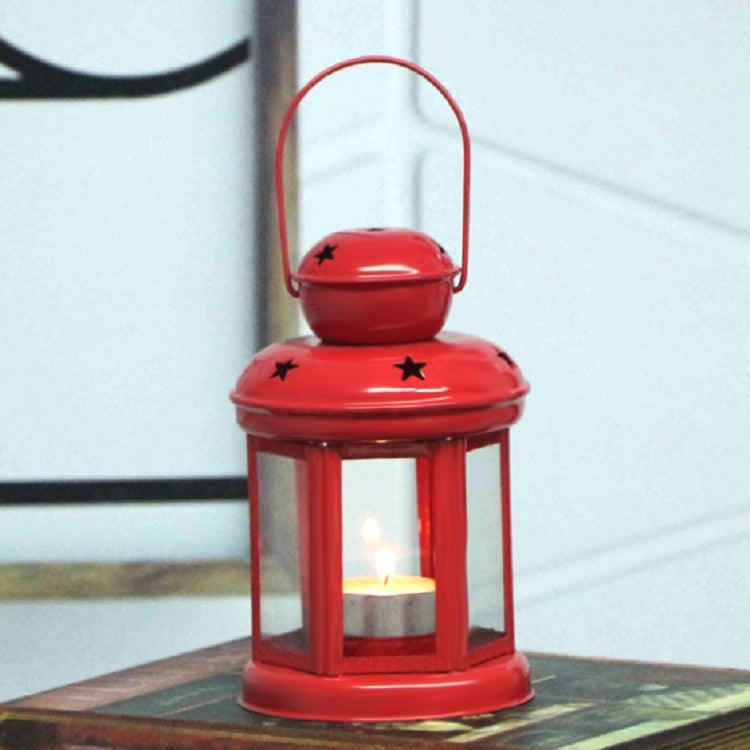 Red metal lantern candle holder with star cutouts and glass sides around a lit candle.