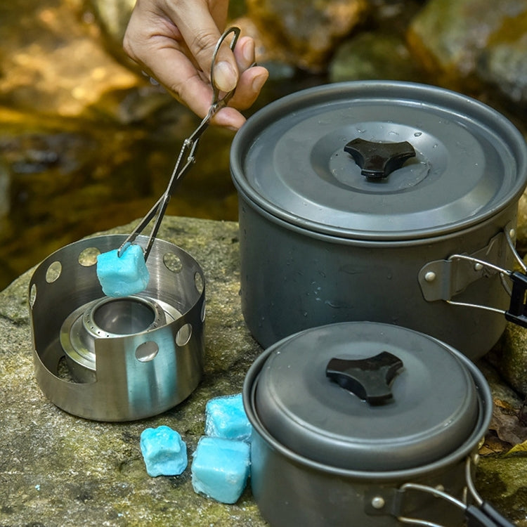 Stainless steel alcohol stove with cover, open burner, and small metal tool